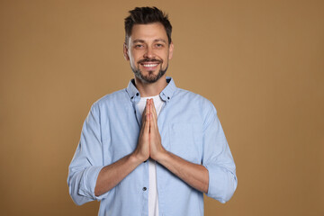 Man with clasped hands praying on beige background