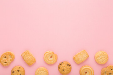 Different dry butter cookies on light pink table background. Pastel color. Closeup. Sweet snacks. Empty place for text. Top down view.