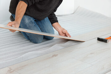 Worker installing new laminate flooring in room, closeup