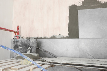 Bucket with cement and putty knifes in room prepared for renovation