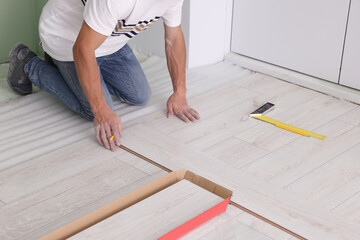 Fototapeta na wymiar Man installing new laminate flooring indoors, closeup