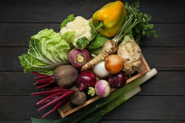 Crate full of different vegetables on black wooden table, top view. Farmer harvesting