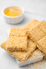 Delicious sesame kozinaki bars and honey on white table, closeup