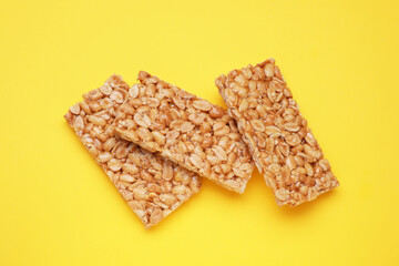 Tasty peanut bars (kozinaki) on yellow background, flat lay