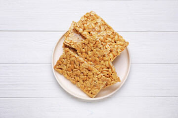 Delicious peanut bars (kozinaki) on white wooden table, top view