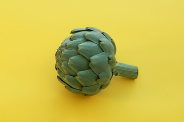 Fototapeta premium Whole fresh raw artichoke on yellow background, closeup