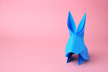 Origami art. Paper rabbit on pink background, space for text