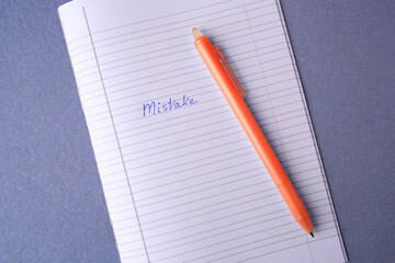 Word Mistake written with erasable pen in copybook on grey background, top view