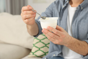 Man with delicious yogurt at home, closeup. Space for text