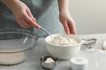 Woman making dough for traditional grissini at light grey marble table indoors, closeup