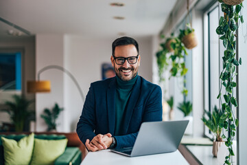 Businessman standing in the office, looking at the camera.