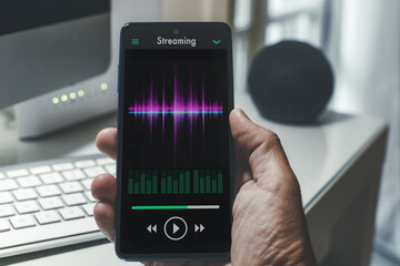 Smartphone in hand playing music. Radio broadcast audio and sharing sound streaming concept.
