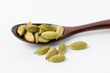 Macro photo of fragrant oriental spices green cardamom pods in brown wooden spoon