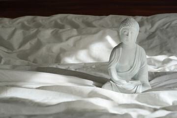 White buddha statue with sunlights on the bed, interior design detail in modern home