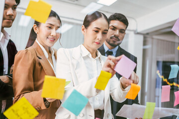 Group of successful Asian businessmen teamwork. Brainstorm meeting with sticky paper notes on the glass wall for new ideas. Using agile methodology for business in a tech start-up office.