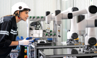 Computer science development engineer working on robot arm connection and control with controller joystick. Woman works in robotic engineering workshop in electronic futuristic technology industrial © Nassorn