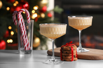 Tasty eggnog, cookies and candy canes on white marble table against blurred festive lights