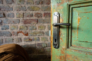 Old door handle on green weathered wooden door