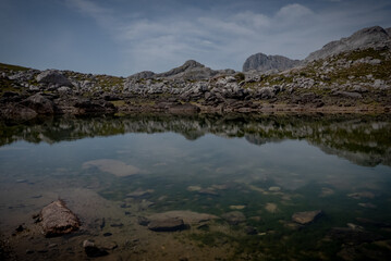 Fototapeta premium Charca protegida con reflejo de la montaña y mas montaña de fondo.