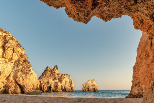 Algarve, Portugal - View of the beach and Alvor from a cave - Cliffs illuminated by the sunset - Summer vacation concept