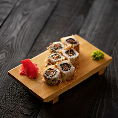 Set of sushi rolls. Baked rolls with baked salmon, wasabi and ginger. Japanese food. Low calorie food. Dark gray wooden background. Side view. Soft focus. Copy space. 