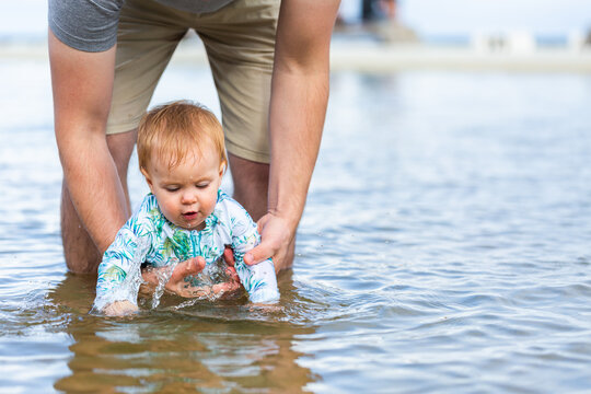 Parent in the water with baby splashing at the seaside