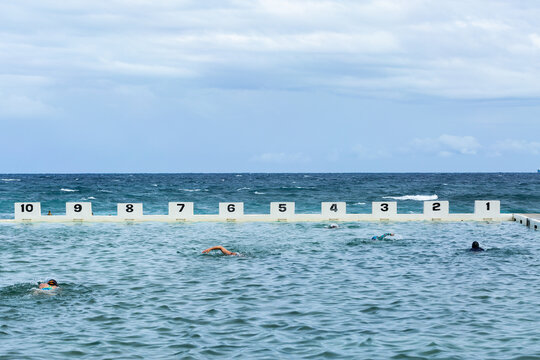 Numbered lane marker at ocean pool with people swimming laps in water