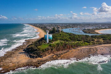 Aerial view of a modern lighthouse on a coastal clifftop next to a water supply tank