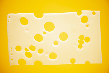 slice of cheese with holes on a yellow background close-up