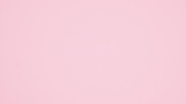 Eating delicious sweet strawberry glazed donut on white plate on pastel pink background. Stop motion. flat lay. Food concept