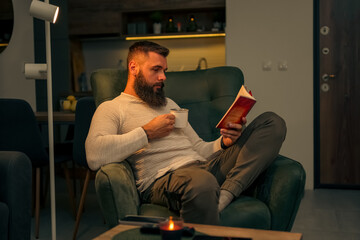 Man watching a movie on his tablet, drinking coffee or tea enjoying some quiet time