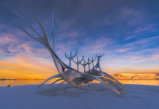 Conceptual metallic sculpture of the Viking boat of The Sun Voyager of the city of Reykjavik from behind from the side, where the full moon and the islands are seen