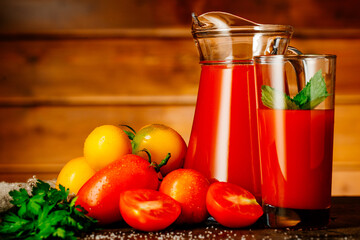 Fresh tomato juice in a glass with tomatoes. Vegetable tomato drink for healthy eating on a wooden background.