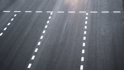 Dotted road lines painted with white dye on black asphalt road. Highway top view.