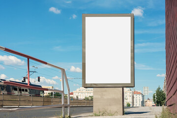 Empty vertical advertisement billboard mounted on urban sidewalk next to tram and bus stop against...