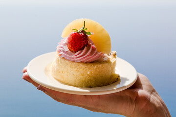 A piece of soft tender cake with pieces pineapple and strawberries on a dish.