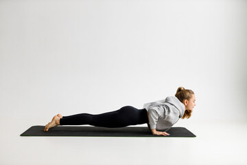 Young woman doing push-ups on a gray background, sports load, everyday workout.