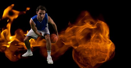 Composition of male basketball player crouching with ball over flames on black background