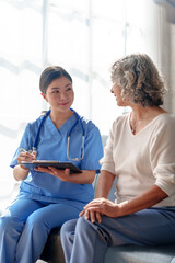 Obraz premium Young asian caretaker with 60s asia elderly woman consulting and encourage, take a history and recommend the right treatment to live happily in retirement, Taking a patient's history