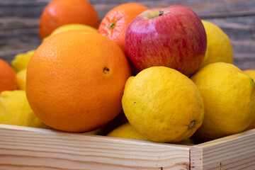 Freshly picked lemons, oranges, tangerines and apples in a Wooden Case.