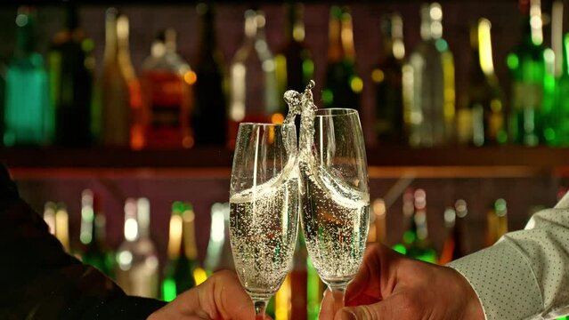 Super slow motion of cheering champagne drinks in bar. Filmed on high speed cinema camera, 1000 fps. Bar with bottles on background.