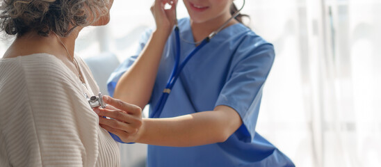 Fototapeta premium Young asian caretaker with 60s asia elderly woman consulting and encourage, take a history and recommend the right treatment, Use a stethoscope to listen to your heartbeat and check for abnormalities.