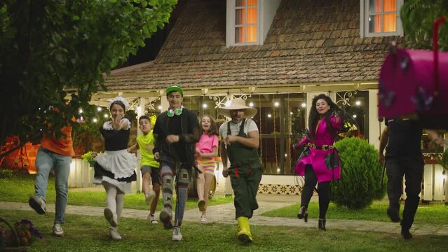 Group of funny , stylish  multi aged dancers dancing near village house at night . Kids dancing with house workers . Multi ethnic people having fun . Beautiful background with different lights .