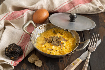 Scrambled eggs with fresh black truffles from Italy served in a frying pan, gourmet breakfast