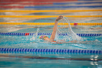 Swimmer child swims backstroke swimming style in the pool - 572249128