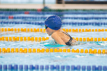 Swimmer child swims breaststroke swimming style in the pool - obrazy, fototapety, plakaty