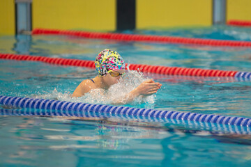 Swimmer child swims breaststroke swimming style in the pool