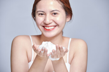 Obraz na płótnie Canvas Asian woman face wash exfoliation scrub soap. Asia girl washing scrubbing with foam skincare cleansing enjoying relaxing time.