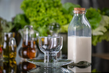 hand hold glass of milk after pours the milk into glass. Serving breakfast fresh milk in glass on glass kitchen table. Front view of healthy drink in breakfast