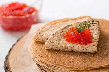 Russian traditions. Russian holiday Maslenitsa. Still life with a stack of pancakes, red caviar, lemon and a sprig of dill.